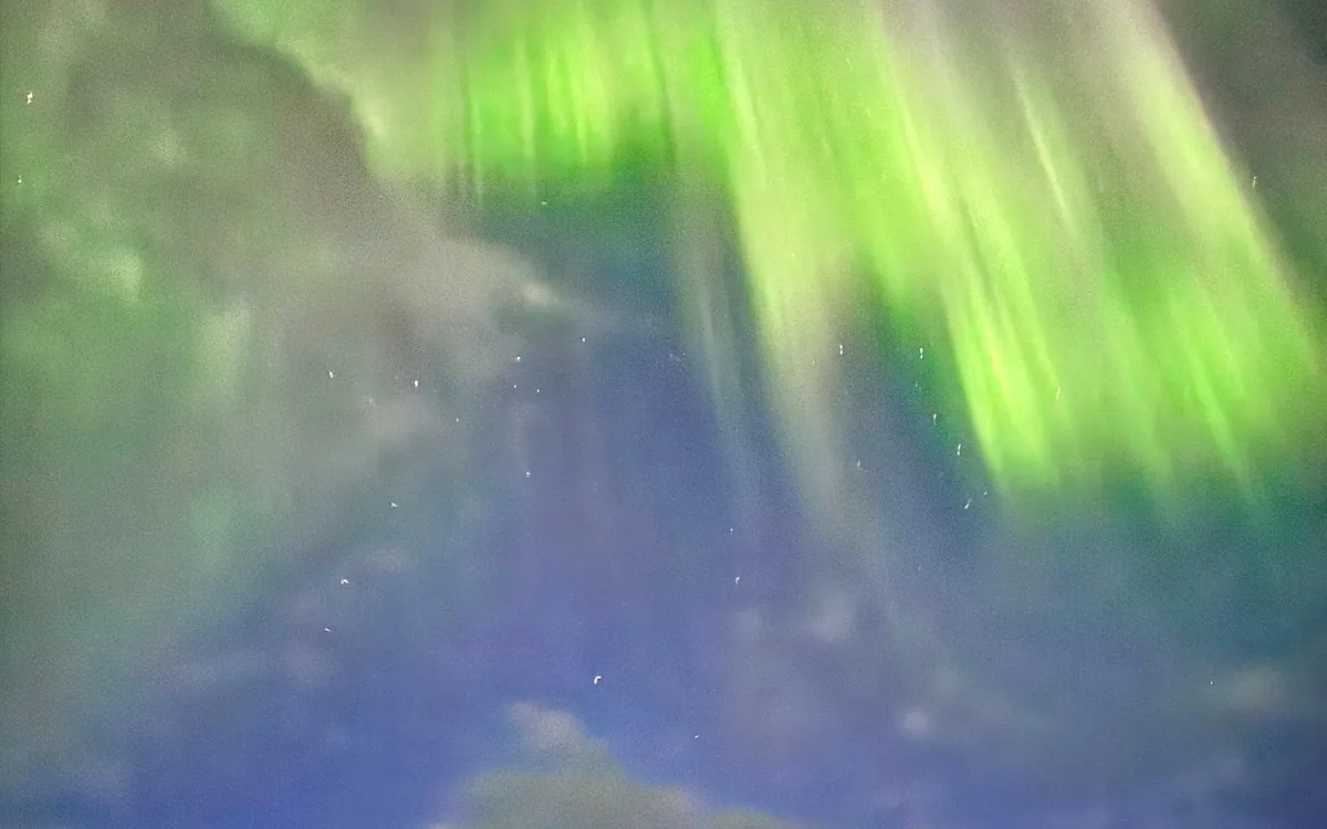 The northern lights above a boat in a fjord near Tromso