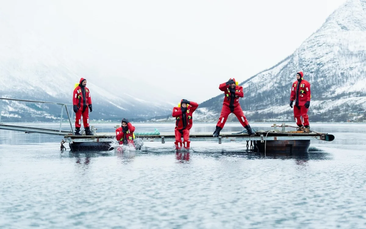 People floating in red survival suits in an Arctic fjord