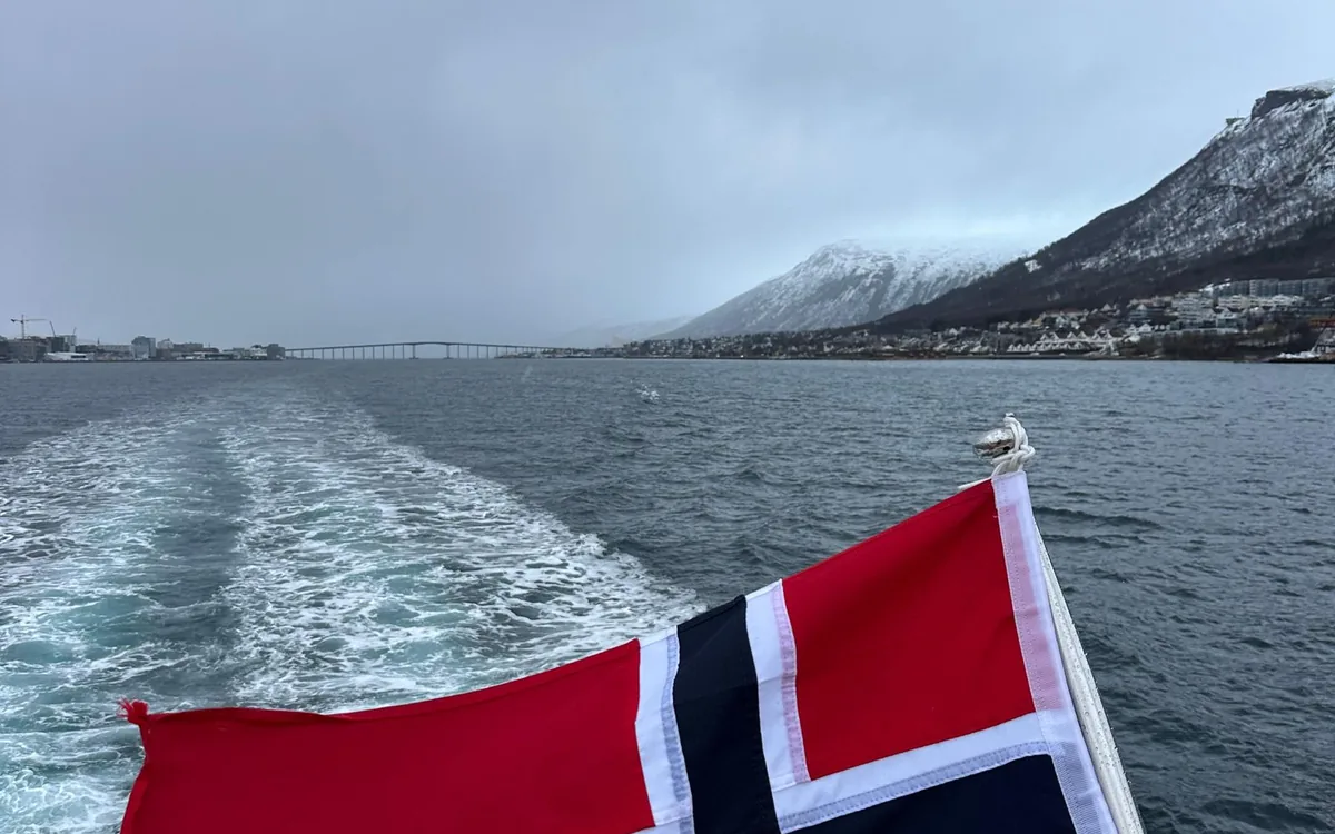 The Norwegian flag on the stern of a boat in an Arctic fjord