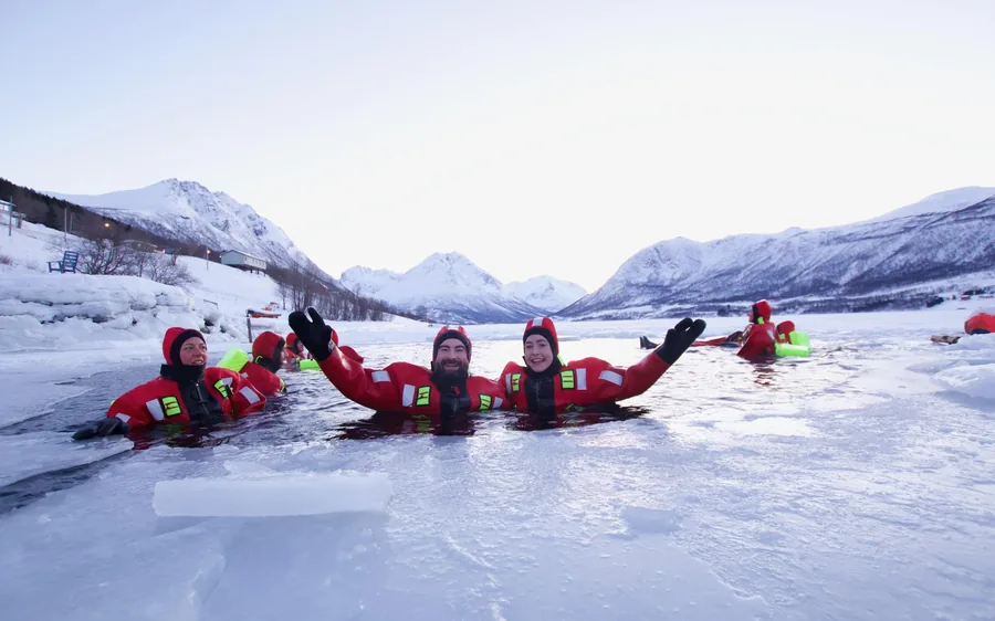 People floating in red survival suits in an Arctic fjord