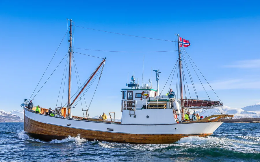 A historic wooden vessel in a fjord near Tromso
