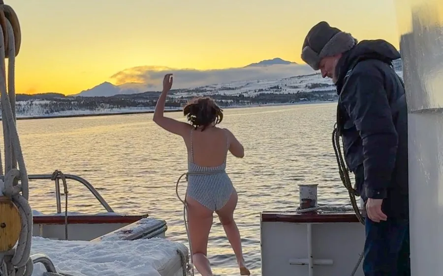A hot tub on the deck of a boat in an Arctic fjord at sunset